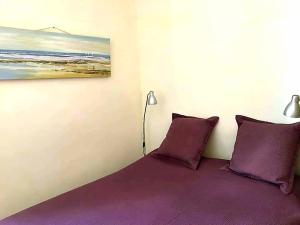 a bedroom with a bed with purple pillows and a painting at Le Machado in Collioure