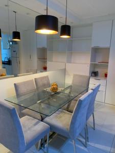 uma sala de jantar com uma mesa de vidro e cadeiras azuis em Apt 2qts 01 suíte BeiraMar PontaVerde Edf Neo 2 1 em Maceió
