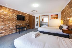 a hotel room with two beds and a brick wall at Clare Central in Clare