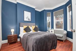 a blue bedroom with a bed and a chair at The Exquisite Leamington Spa House - Sleeps 8 in Leamington Spa