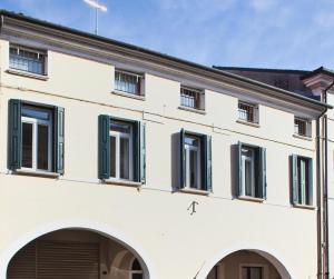 un edificio blanco con ventanas con contraventanas verdes en B&B ViaCavourSei, en Portogruaro