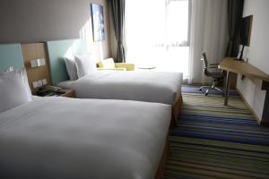 a hotel room with two beds and a window at Holiday Inn Express Yingkou Onelong Plaza, an IHG Hotel in Gaizhou