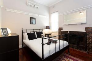 Schlafzimmer mit einem schwarzen und weißen Bett und einem Kamin in der Unterkunft Solomon Street Cottage in Fremantle