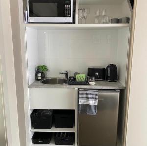 a small kitchen with a sink and a microwave at L'École Private Studio-Apartment by My Lodgingfy in Moorabbin