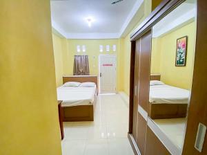 a room with two beds and yellow walls at Damigalova Guest House Mitra RedDoorz in Jambi