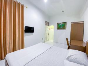 a bedroom with a bed and a desk and a television at Damigalova Guest House Mitra RedDoorz in Jambi