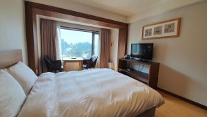 Habitación de hotel con cama y TV en Gyungpo Beach Hotel, en Gangneung