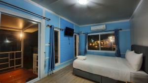 um quarto azul com uma cama e uma janela em Phalagoon Resort em Ban Chang