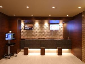 una sala de espera con banco y TV en Dormy Inn Ikebukuro, en Tokio