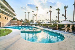 a pool at a hotel with palm trees in the background at Grand Josun Jeju in Seogwipo