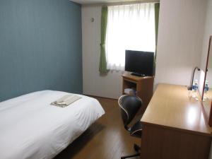 福岡市にある シーサイドホテルツインズももちのベッド、デスク、テレビが備わるホテルルームです。