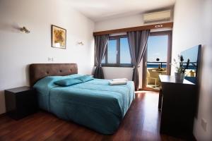 a bedroom with a bed and a desk and window at Pigeon Beach Hotel Apartments in Limassol