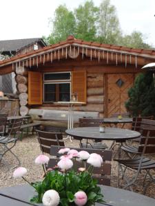 a cabin with tables and chairs and pink flowers at Gasthaus Post in Goldbach