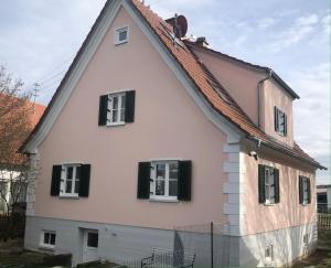 Casa blanca grande con ventanas con persianas negras en Ferienwohnung Kröner, en Donauwörth