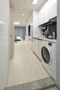 a kitchen with white cabinets and a washing machine at Bayone Park in Yeosu