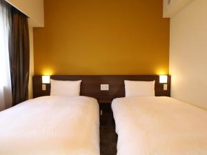 
a hotel room with two beds and two lamps at Dormy Inn Ikebukuro in Tokyo
