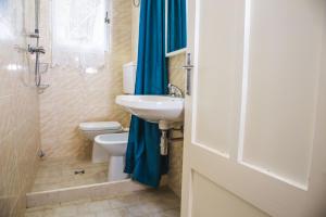 ein Badezimmer mit einem Waschbecken, einem WC und einem blauen Duschvorhang in der Unterkunft Casa Zanelli in Lignano Sabbiadoro