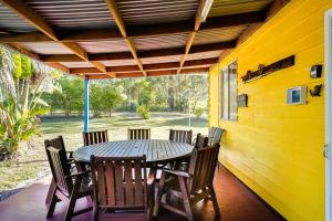 a table and chairs on the porch of a house at Yellow Cottage - bush and beach in Agnes Water