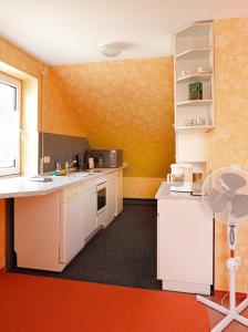 a kitchen with white cabinets and an orange wall at Private Ferienwohnungen in Fürth bei Nürnberg in Fürth