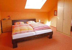 a bed in a bedroom with an orange wall at Private Ferienwohnungen in Fürth bei Nürnberg in Fürth