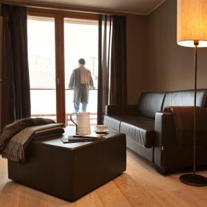 a man looking out the window of a living room at Grand Hotel Paradiso in Passo del Tonale