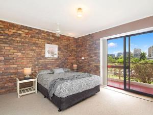 a bedroom with a brick wall and a bed and a window at Coral Gardens Unit 2 in Coolangatta