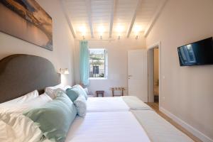una camera da letto con un grande letto bianco con cuscini blu di Melina's Urban Retreat a Città di Corfù