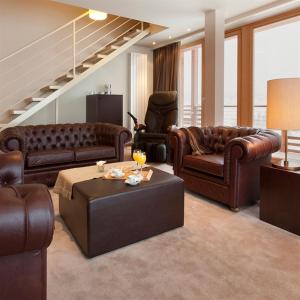 a living room with leather couches and a table at Grand Hotel Paradiso in Passo del Tonale