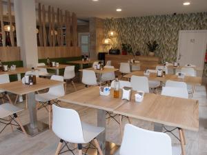 a restaurant with wooden tables and white chairs at Hospedium Hotel Abril in San Juan de Alicante