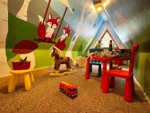 ein Kinderspielzimmer mit Spielzeugfahrzeugen und einem Tisch in der Unterkunft Haus am Berg - Pension direkt am Skihang in Kurort Oberwiesenthal