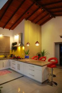 una cucina con armadietti bianchi e sgabelli rossi da bar di Colombo Orchid Villa a Colombo