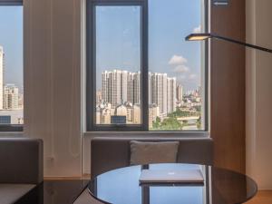 um quarto com uma mesa de vidro e uma grande janela em GreenTree Eastern Binhu Road Wanda Hotel em Nanning