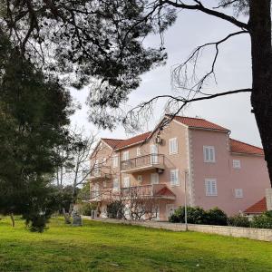 ein großes rosafarbenes Gebäude in einem Park mit Hof in der Unterkunft Ruzica Apartments in Mirce