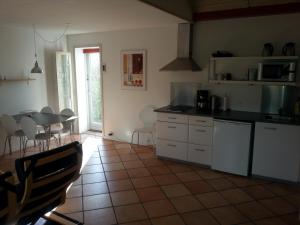 uma cozinha com armários brancos e uma mesa com cadeiras em Aarhus Syd Holiday Apartment em Beder