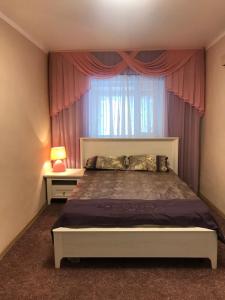 エイスクにあるHoliday Home on Pushkina 24のベッドルーム1室(ベッド1台付)、ピンクのカーテン付きの窓が備わります。