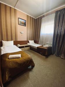ロストフ・ナ・ドヌにあるコンチネンタル ホテルのベッド2台と窓が備わるホテルルームです。