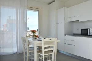 a white kitchen with a table and chairs and a microwave at Residence Al Molo - Agenzia Cocal in Caorle +46 photos