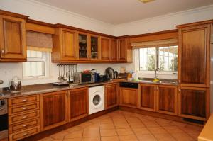 cocina con armarios de madera, lavadora y secadora en Albufeira Villa Okapi, en Albufeira