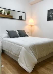 un grande letto bianco in una stanza bianca con una lampada di Apartamento Centro Histórico a Pontevedra