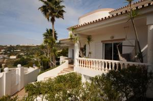 a white house with a balcony with palm trees at Albufeira Villa Okapi in Albufeira