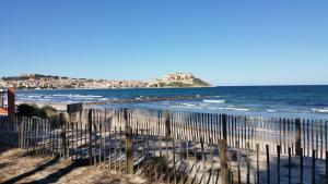 a beach with a fence and the ocean at Camping La Pinède in Calvi