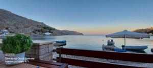 a table with an umbrella and boats on the water at Symi . VILLA CALME (Sur la Mer). in Symi