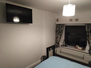 a bedroom with a bed and a tv on the wall at Wheelgate in Torver