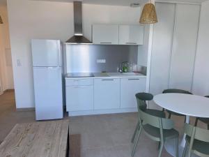 a kitchen with a white refrigerator and a table at Résidence Marina Di Bravone in Linguizzetta
