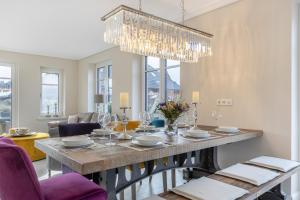 una sala da pranzo con tavolo, sedie e lampadario pendente di Hüs Maxi a Wenningstedt