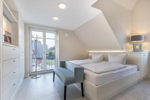 una camera bianca con un letto e una finestra di Hüs Maxi a Wenningstedt