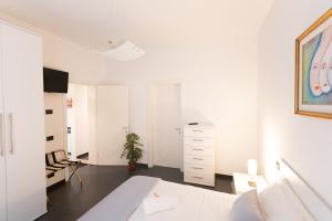 biała sypialnia z łóżkiem i komodą w obiekcie Cà Sottomarina gli Appartamenti in Centro Apartsuite w mieście Sottomarina