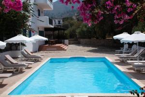 a pool with chairs and umbrellas next to a building at Boutique Hotel Tilos Mare in Livadia