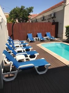 uma fila de espreguiçadeiras azuis e brancas junto a uma piscina em Casas de Luanda GH-Miramar em Luanda
