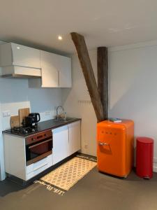 a kitchen with an orange refrigerator and white cabinets at Uitzicht op de haven in Kollum